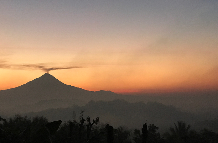 Amanhecer na salva de Java com vulcão ativo ao fundo